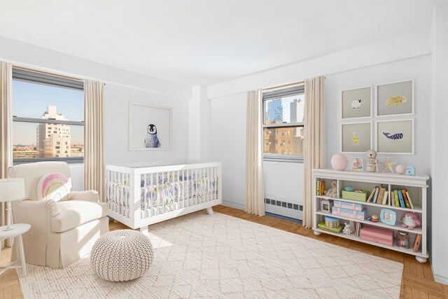 bedroom featuring a nursery area and parquet floors