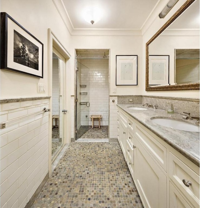 bathroom with a shower with door, crown molding, tile walls, and vanity