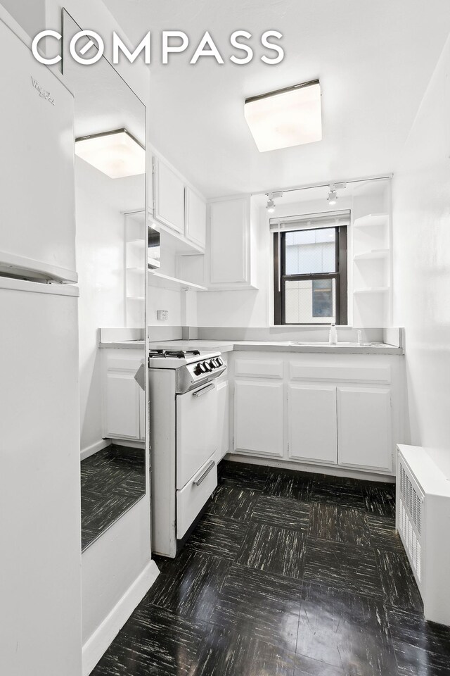 kitchen with refrigerator, white electric range, radiator, and white cabinets