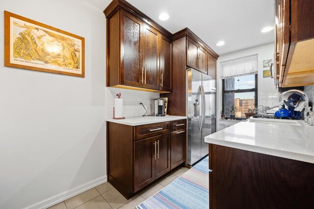 kitchen featuring dark brown cabinets, stainless steel fridge with ice dispenser, decorative backsplash, and light tile patterned floors