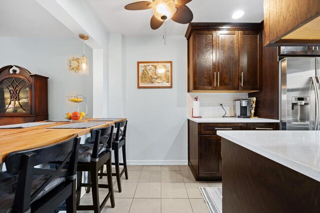 kitchen featuring stainless steel refrigerator with ice dispenser, light tile patterned flooring, tasteful backsplash, decorative light fixtures, and ceiling fan