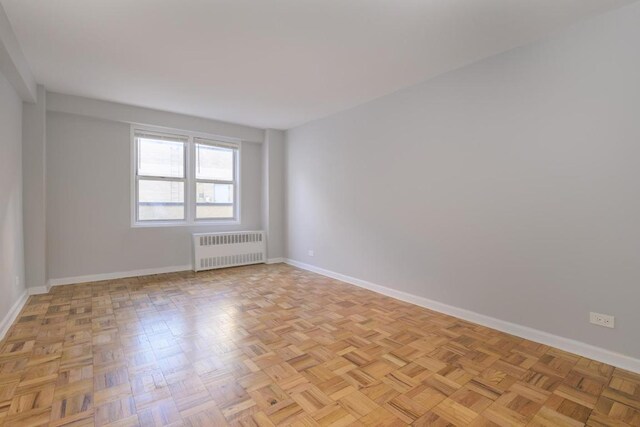 spare room featuring light parquet floors and radiator