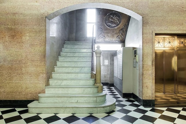 staircase featuring baseboards, mail area, and tile patterned floors