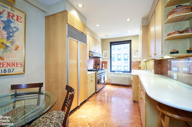 kitchen with tasteful backsplash, premium appliances, sink, and light brown cabinets