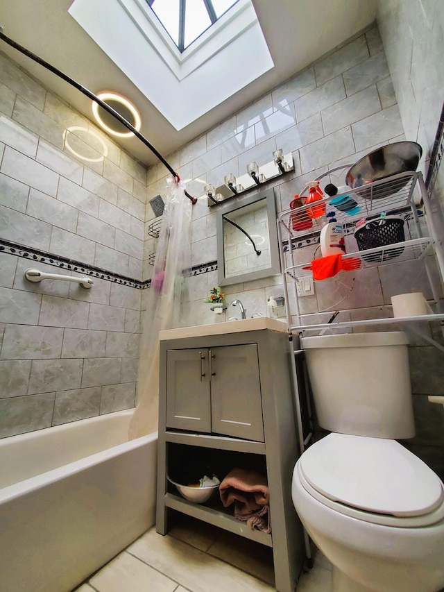 full bath with a skylight, tile walls, tile patterned flooring, and vanity
