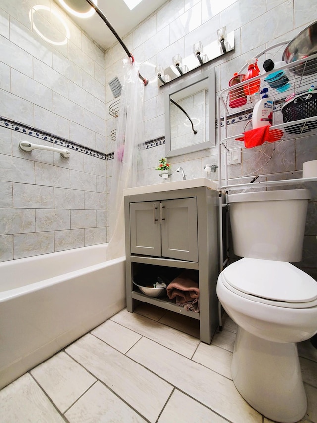 bathroom with vanity, toilet, tile patterned floors, shower / bathtub combination with curtain, and tile walls