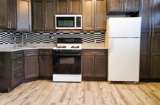 kitchen featuring range with gas stovetop, freestanding refrigerator, stainless steel microwave, a sink, and backsplash