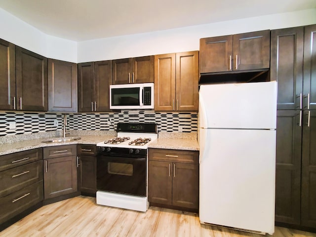 kitchen with a sink, tasteful backsplash, freestanding refrigerator, and gas range oven