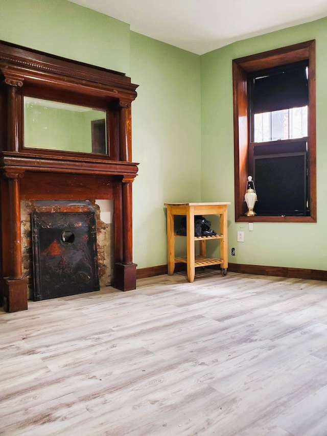 unfurnished living room with baseboards, wood finished floors, and a fireplace