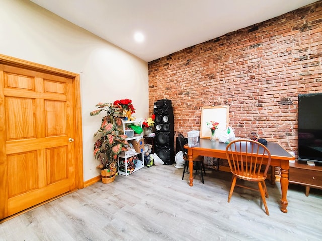 office area with baseboards, brick wall, and wood finished floors