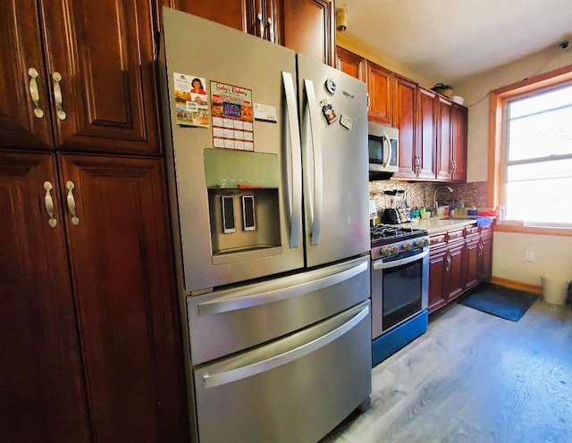 kitchen with tasteful backsplash, sink, light hardwood / wood-style flooring, and stainless steel appliances