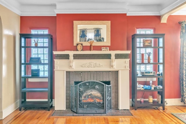 room details featuring wood-type flooring, a brick fireplace, and ornamental molding