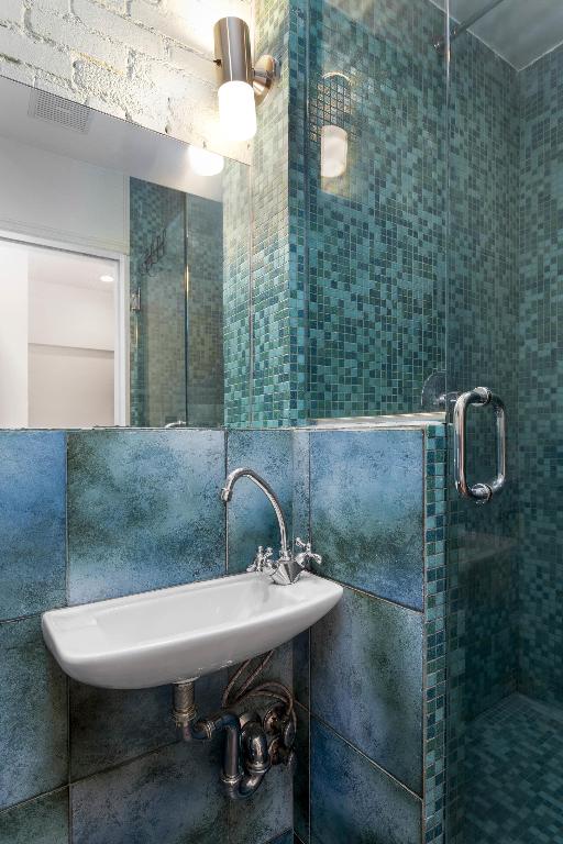 full bath featuring a stall shower, a sink, and tile walls