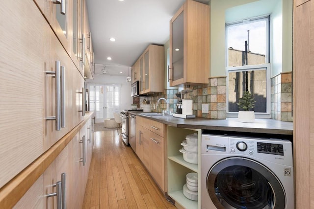 kitchen with open shelves, stainless steel appliances, washer / clothes dryer, glass insert cabinets, and a sink