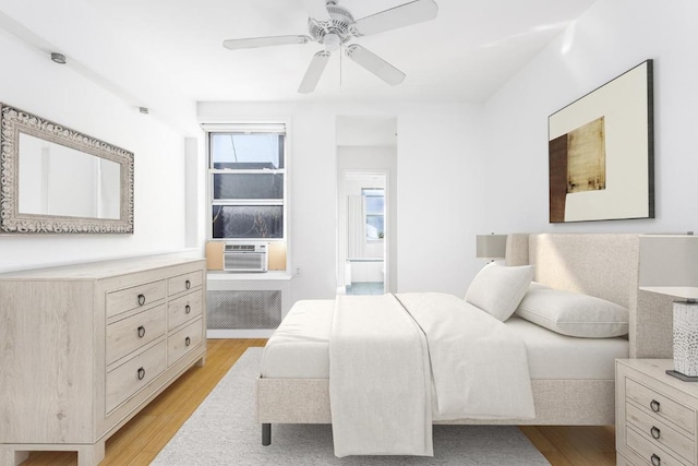 bedroom with a ceiling fan, cooling unit, and light wood finished floors