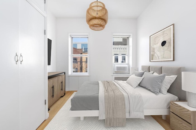 bedroom with cooling unit and light wood finished floors