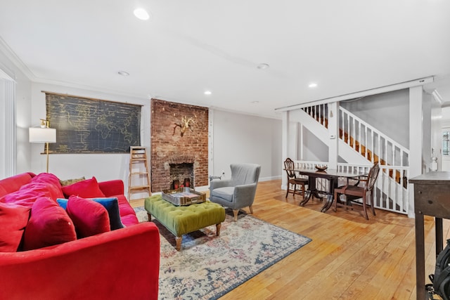 living room with wood-type flooring, a brick fireplace, and crown molding