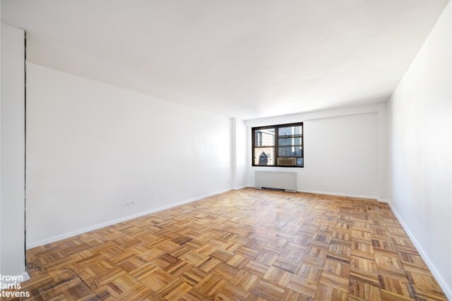 spare room featuring light parquet floors and radiator heating unit