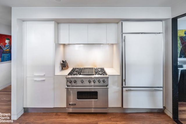 kitchen with white cabinetry, high end appliances, light countertops, and wood finished floors