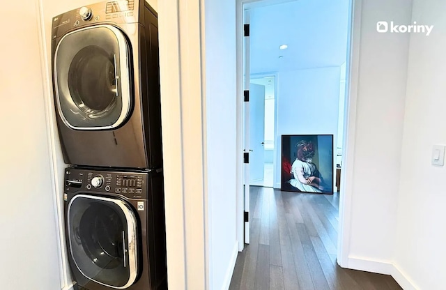 laundry area featuring stacked washer / dryer and dark hardwood / wood-style flooring