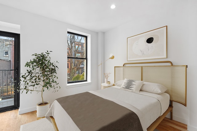 bedroom with access to outside, recessed lighting, wood finished floors, and baseboards