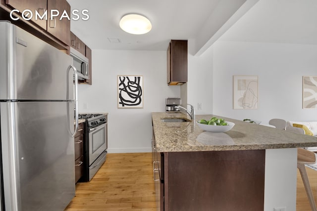 171 W 131st St Unit 304, New York City, NY 10027 - kitchen featuring stainless steel appliances, a breakfast bar, light wood-style flooring, and a peninsula