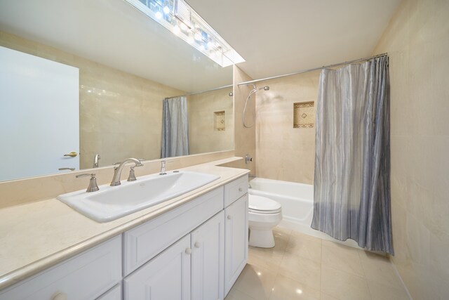 full bathroom with shower / tub combo, tile patterned flooring, tile walls, vanity, and toilet