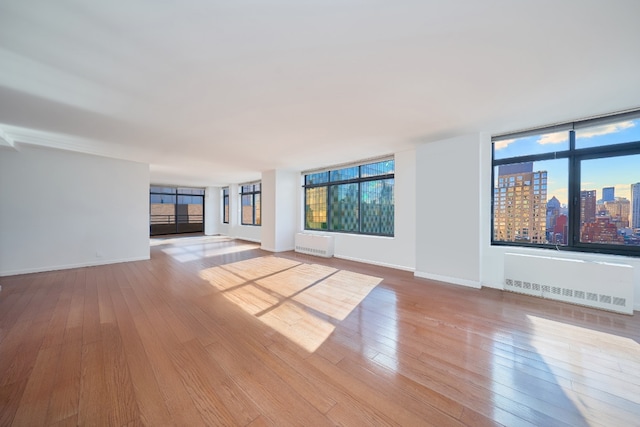 unfurnished living room with radiator heating unit and light wood-type flooring