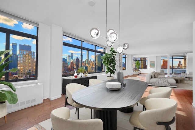 dining area featuring an inviting chandelier, radiator, and light hardwood / wood-style floors