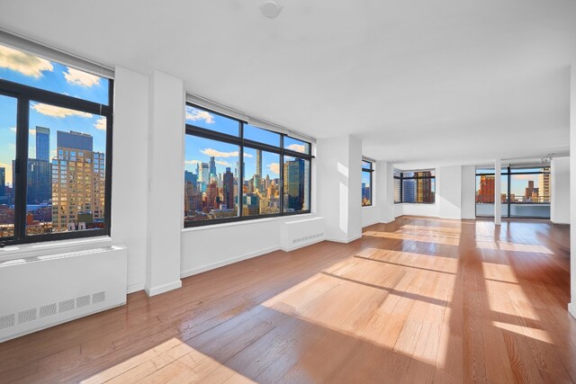 unfurnished living room featuring radiator and hardwood / wood-style flooring