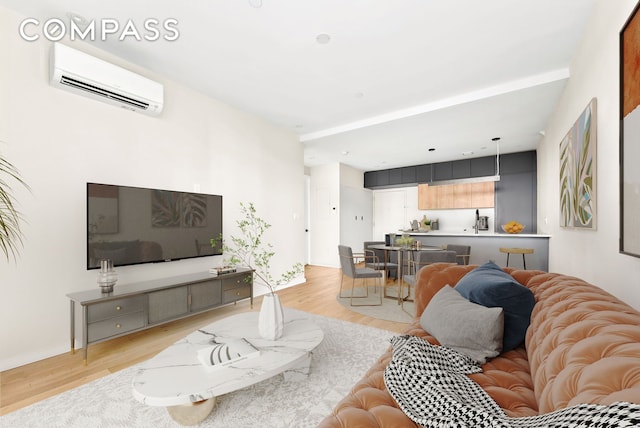 living area with a wall mounted AC, light wood-type flooring, and baseboards