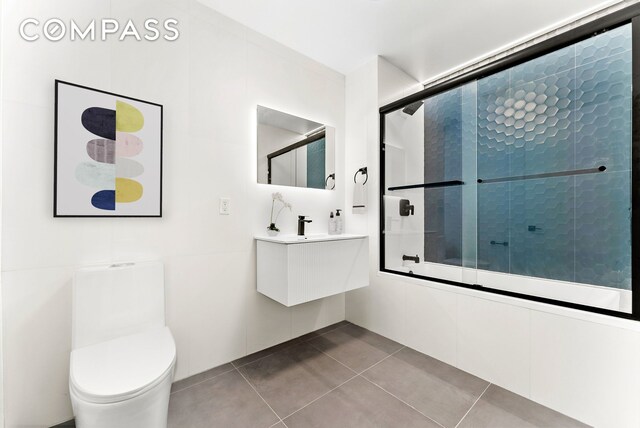 bathroom featuring tile patterned flooring, enclosed tub / shower combo, and toilet