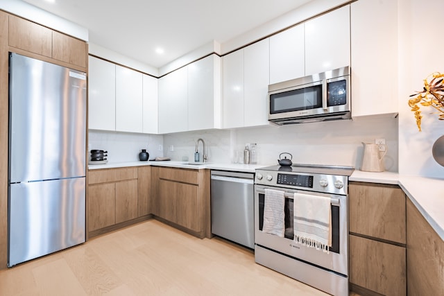 kitchen with stainless steel appliances, a sink, light countertops, white cabinets, and recessed lighting
