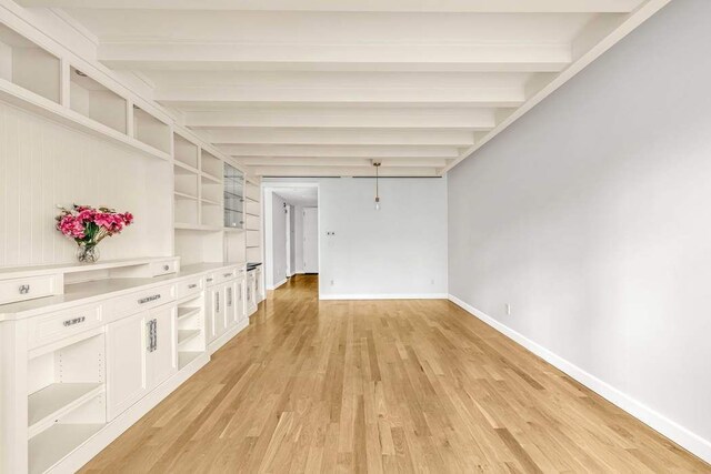 unfurnished bedroom with beamed ceiling, coffered ceiling, light wood-type flooring, and a notable chandelier