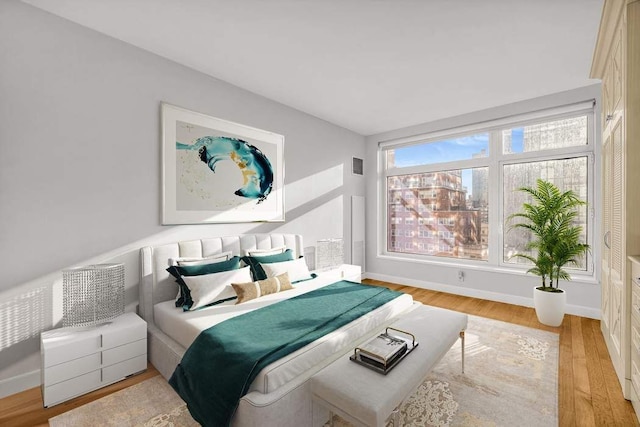 bedroom featuring light wood-type flooring, baseboards, and visible vents