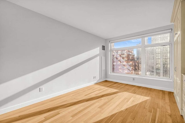 unfurnished room with visible vents, light wood-style flooring, and baseboards