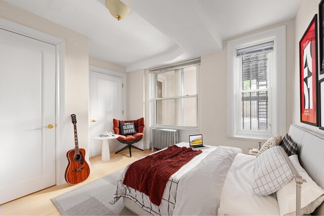 bedroom with radiator heating unit and wood finished floors