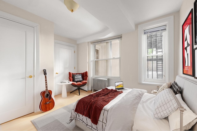 bedroom with radiator and wood finished floors