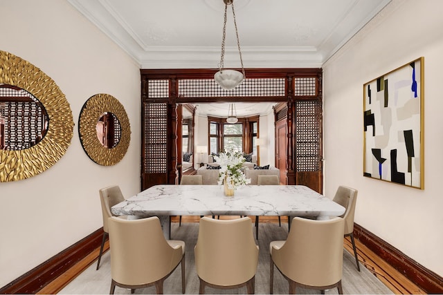 dining area featuring baseboards, light wood-style floors, and ornamental molding