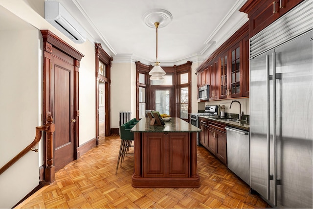 kitchen featuring a wall unit AC, a kitchen island, appliances with stainless steel finishes, radiator, and glass insert cabinets