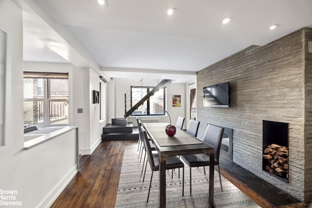 dining room with dark wood-type flooring and a large fireplace