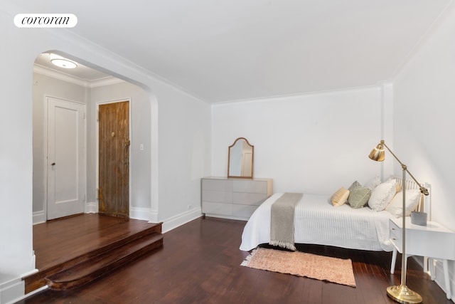 bedroom with wood finished floors, arched walkways, ornamental molding, and baseboards