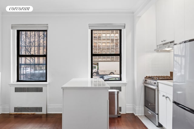 kitchen with dark hardwood / wood-style flooring, radiator, tasteful backsplash, appliances with stainless steel finishes, and white cabinets