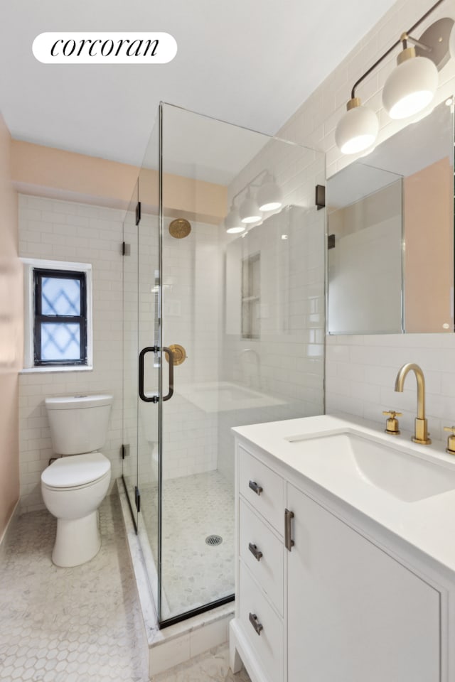 full bath featuring toilet, vanity, a stall shower, tile patterned floors, and tile walls