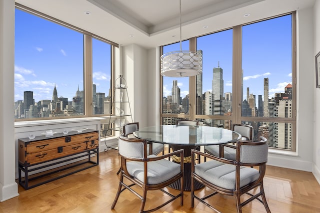 dining room featuring a city view, a wealth of natural light, baseboards, and a tray ceiling
