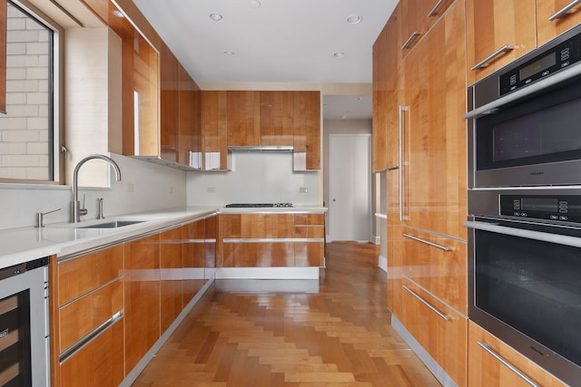 kitchen with brown cabinetry, wine cooler, modern cabinets, light countertops, and a sink