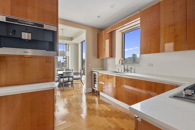 kitchen featuring light countertops, modern cabinets, brown cabinets, a sink, and beverage cooler