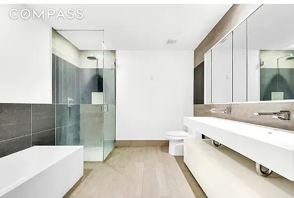 540 W 49th St Unit 406N, New York City, NY 10019 - full bathroom with a freestanding tub, a stall shower, toilet, and baseboards