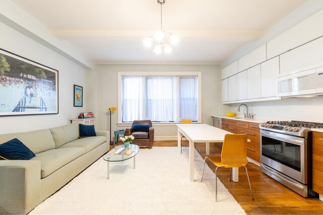 living room with sink, a notable chandelier, and light hardwood / wood-style flooring