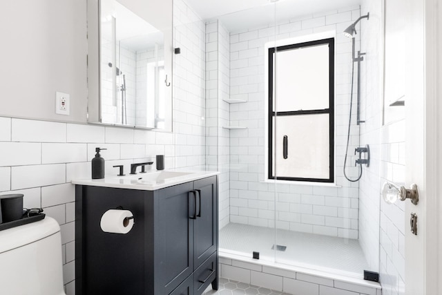 full bath featuring toilet, a stall shower, tile walls, and vanity